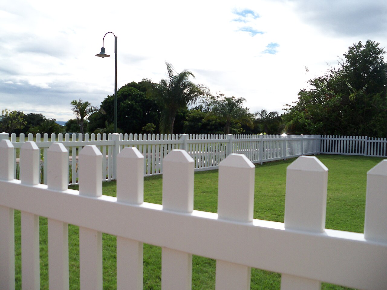 White PVC picket fence with palms